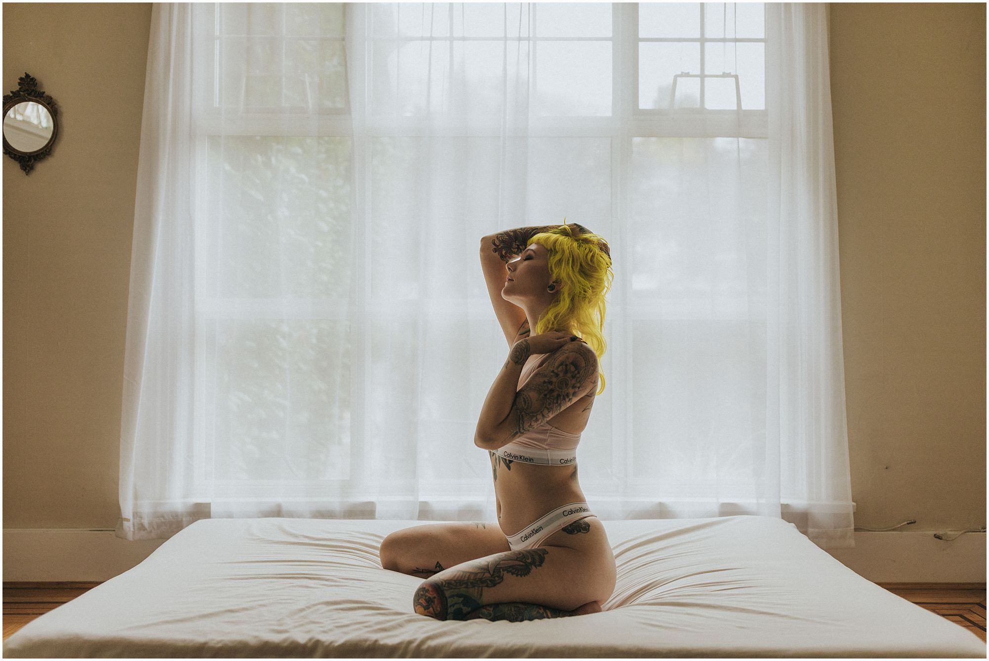 alternative model with bright yellow hair poses on bed during boudoir shoot with vancouver boudoir photographer