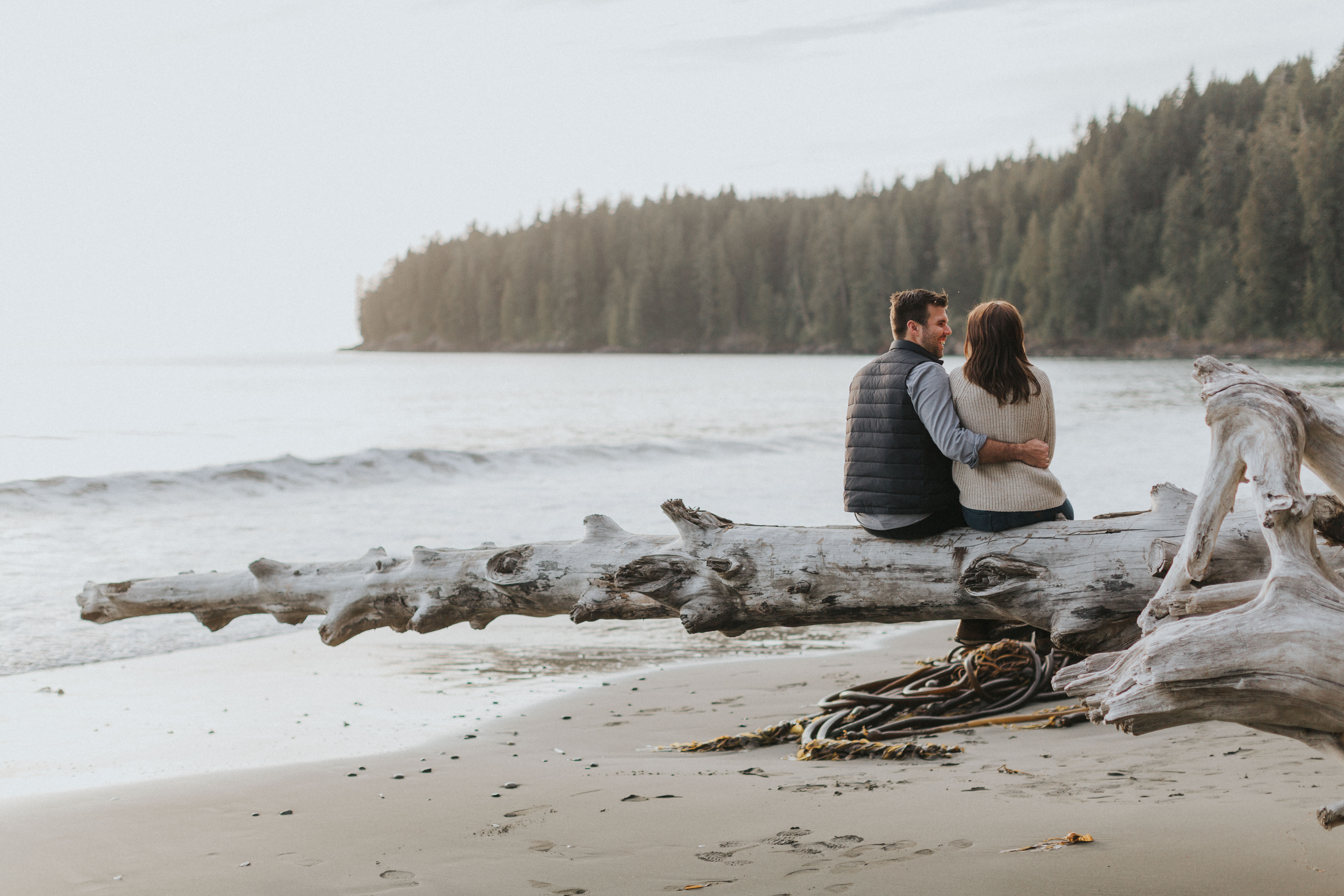 engaged couple sitting on the beach - vancouver wedding photographer